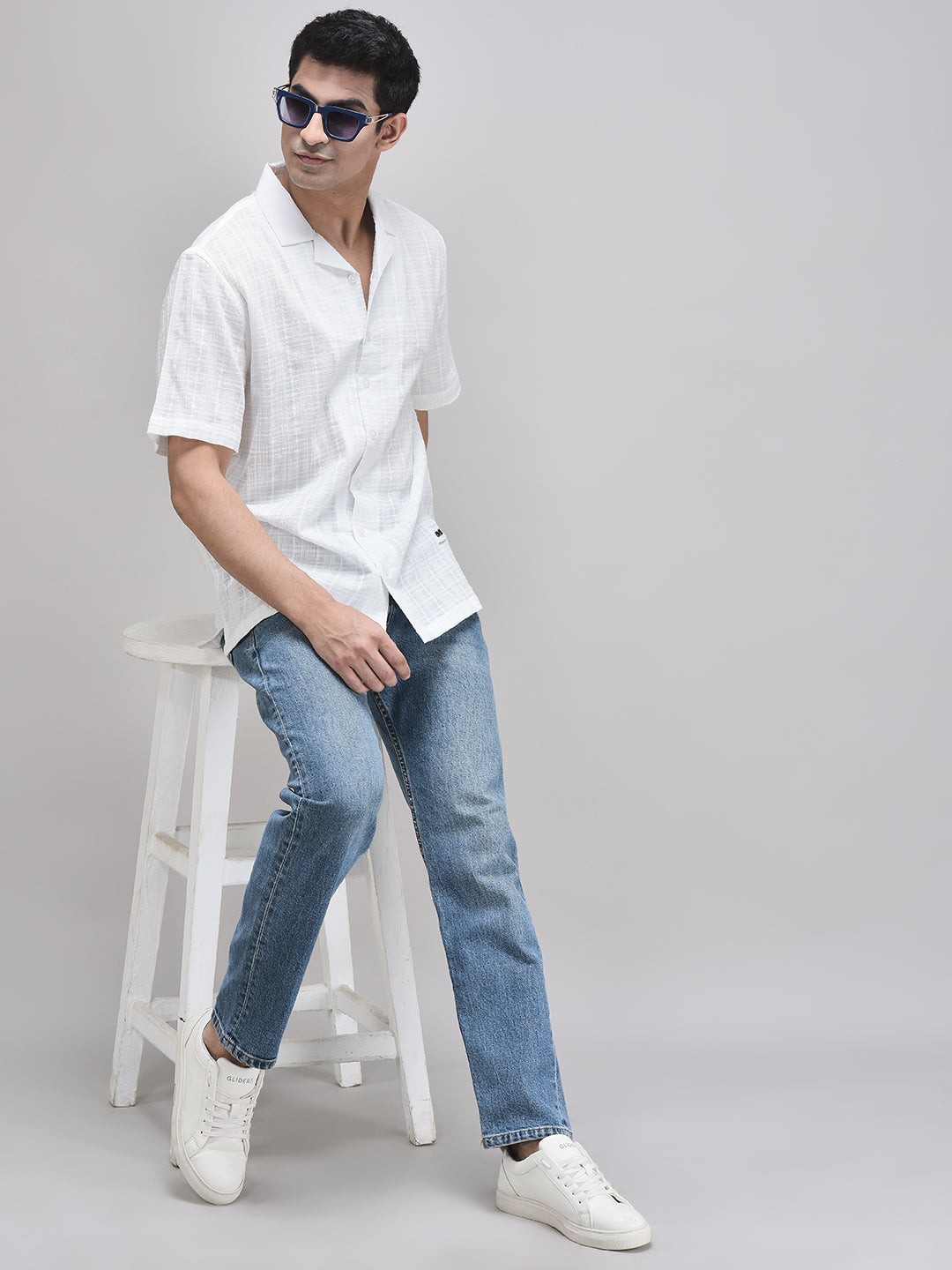 Full body shot of man walking in white cotton shirt and blue jeans – casual summer styling