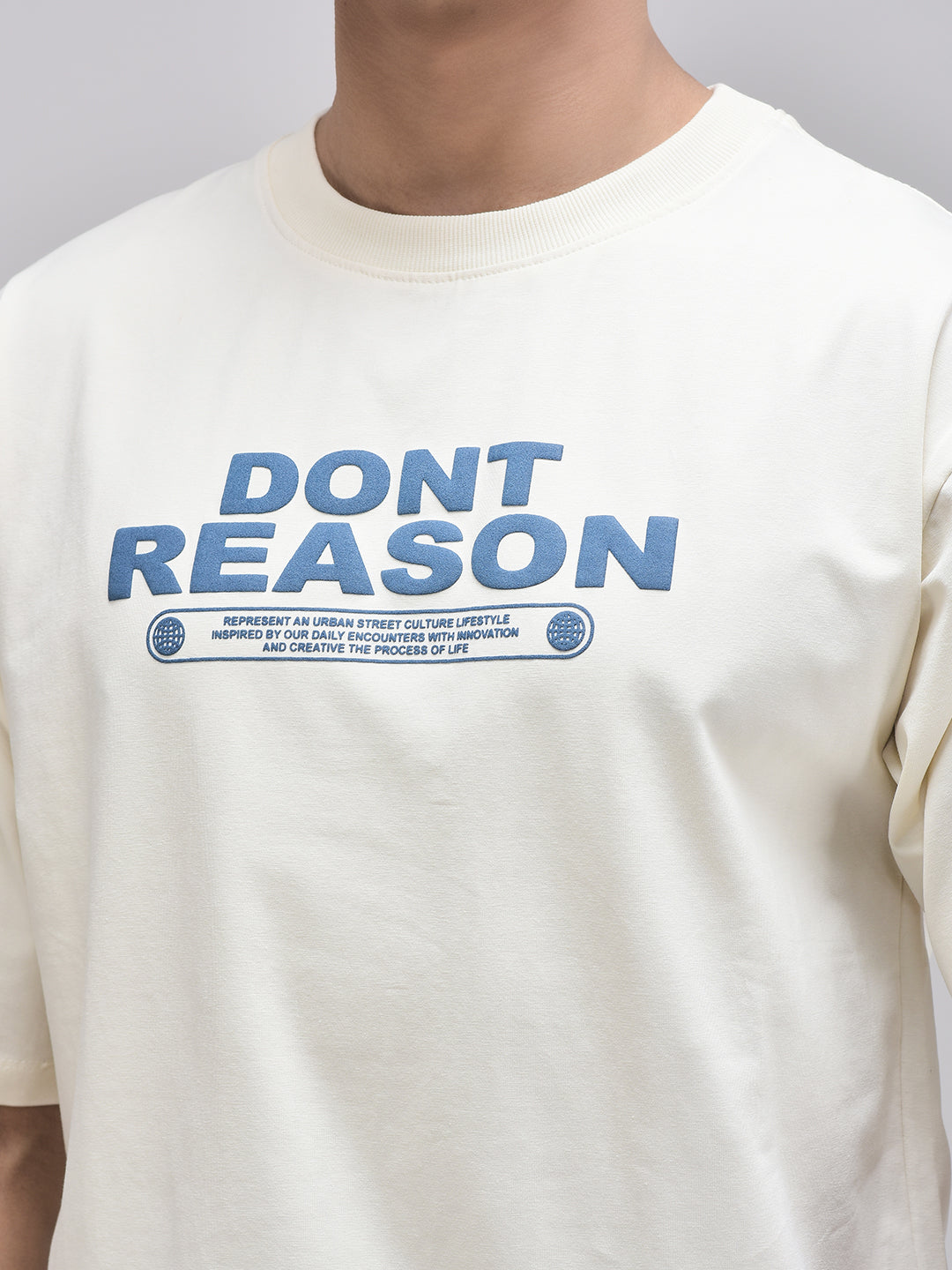 Zoomed-in puffer print on Don’t Reason beige t-shirt – bold blue typography
