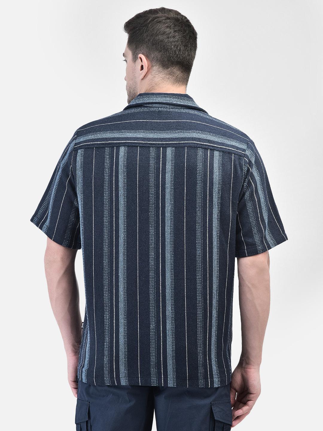 Back view of man wearing navy blue striped shirt – relaxed resort look