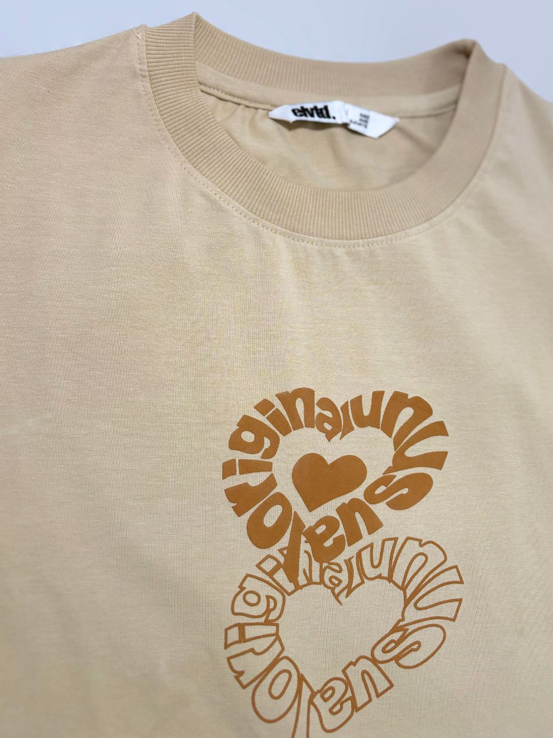 Beige t-shirt with brown graphic design and text