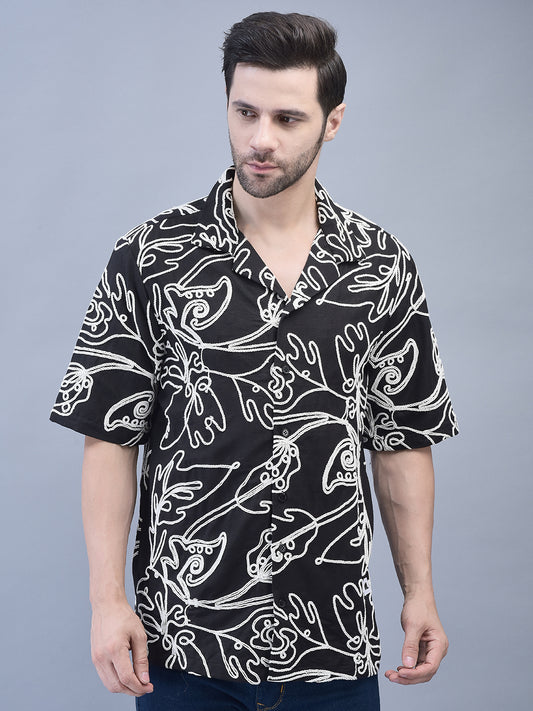 A man wearing a black and white floral patterned shirt with short sleeves and a crew neck.