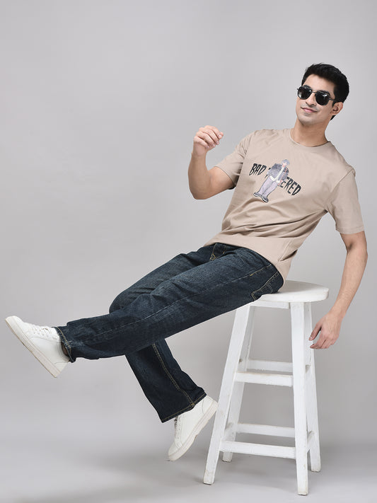 Oversized brown graphic t-shirt styled with black jeans – seated streetwear look