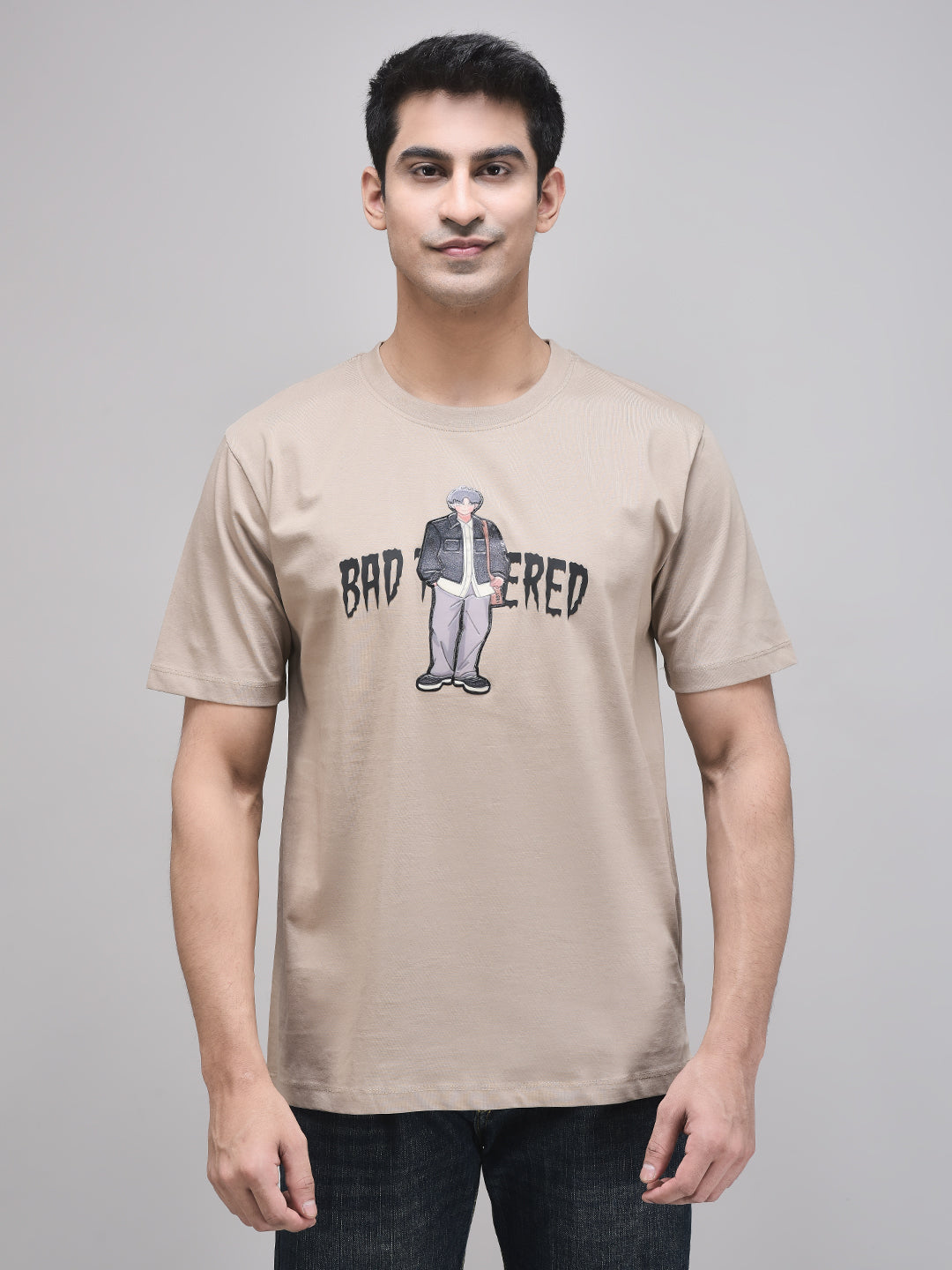 A male model wearing a beige oversized t-shirt with the text 'BAD TEMPERED' and a graphic print.
