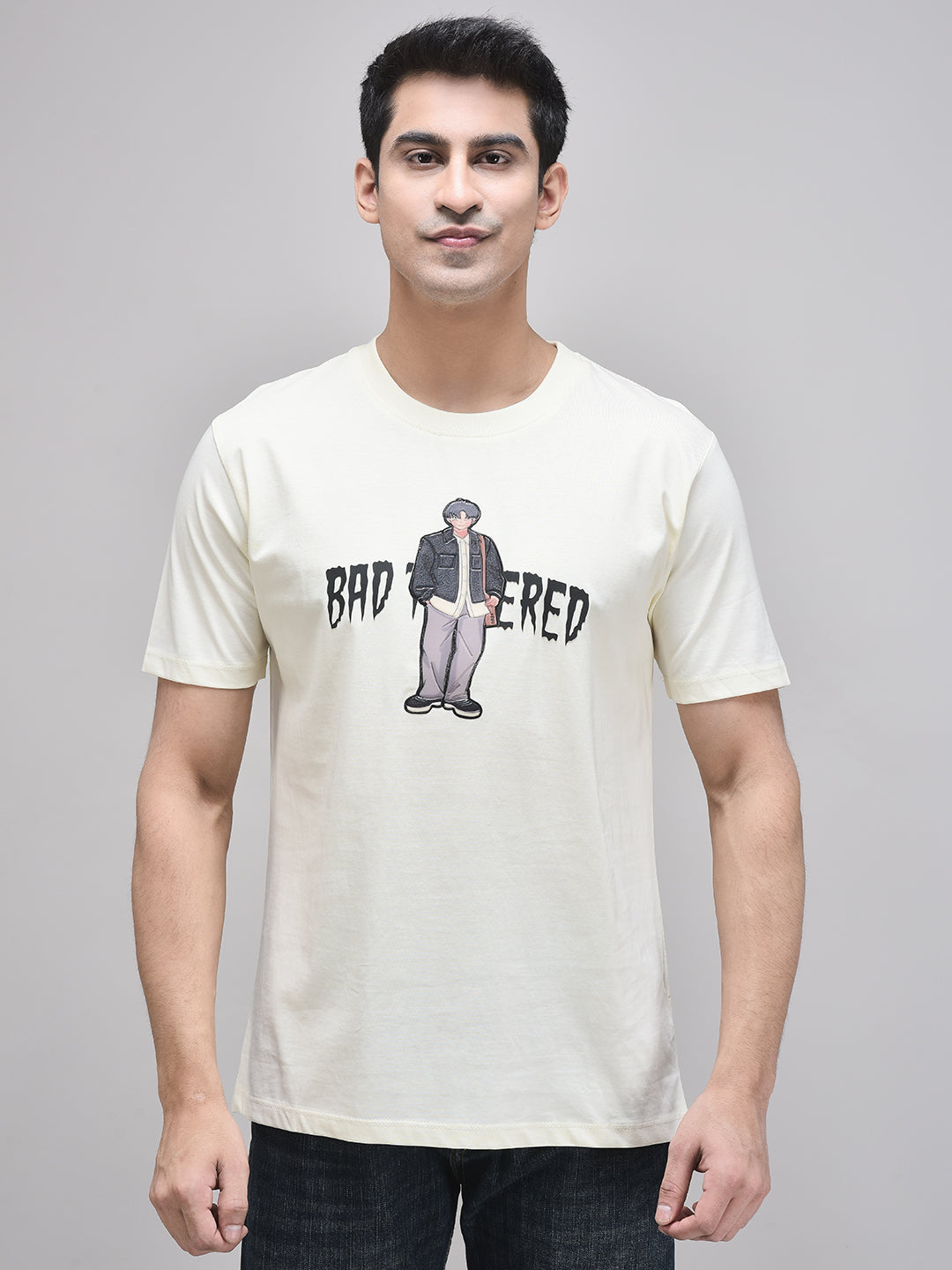 A male model wearing a beige t-shirt with a graphic print in the center, standing against a plain background.