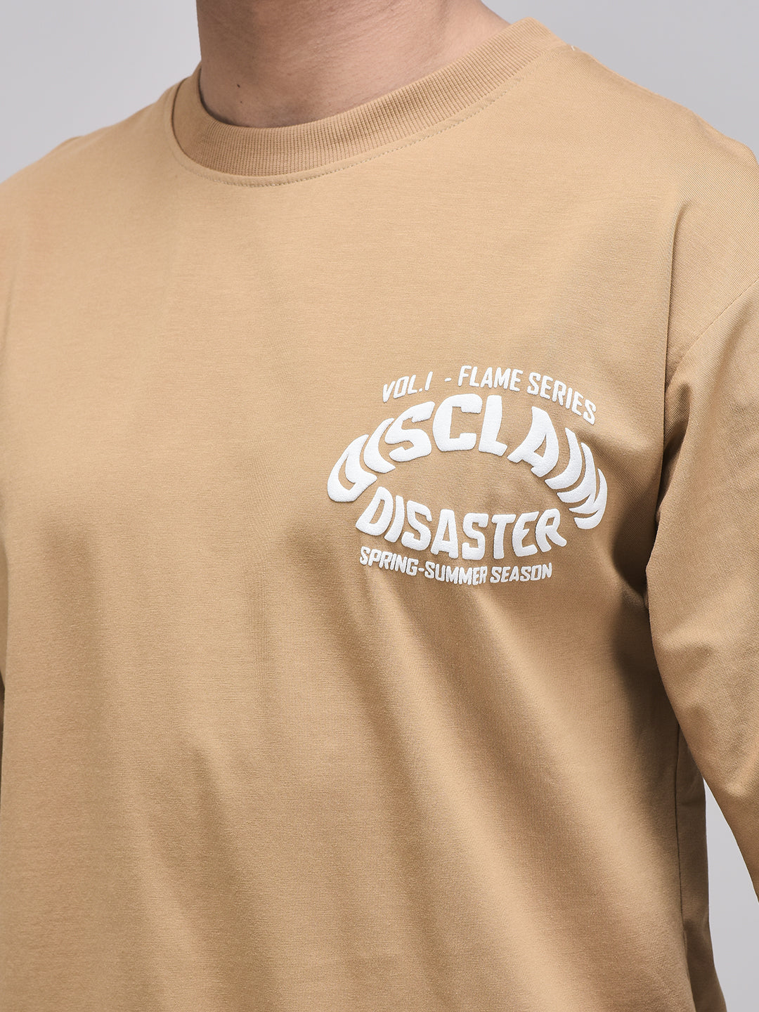 Zoomed-in Disclaim Disaster front chest print on mocha brown cotton fabric
