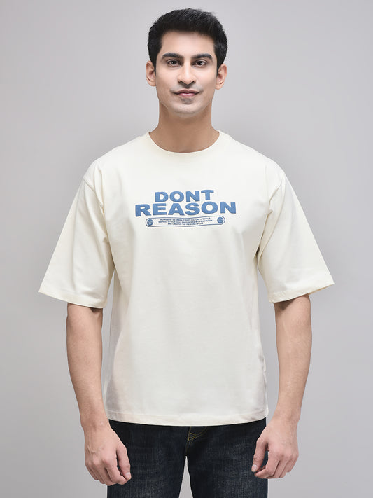 A male model wearing a beige oversized t-shirt with the text 'DON'T REASON' printed in bold letters on the front.