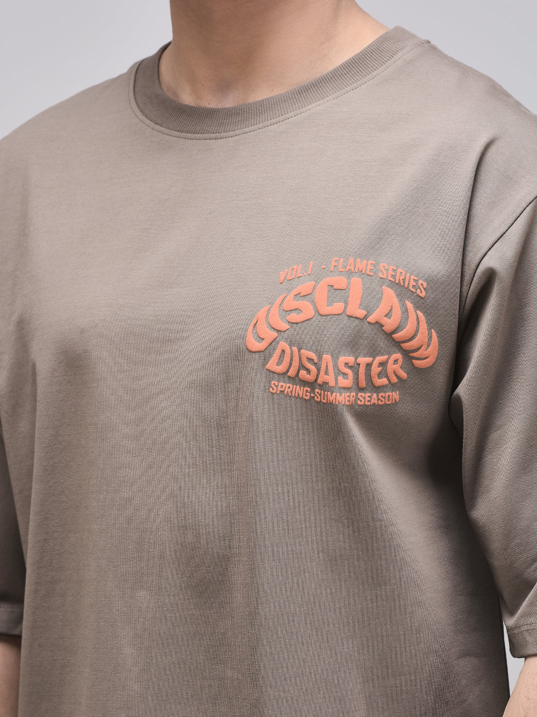 Zoomed-in Disclaim Disaster chest print on claystone t-shirt – orange typography
