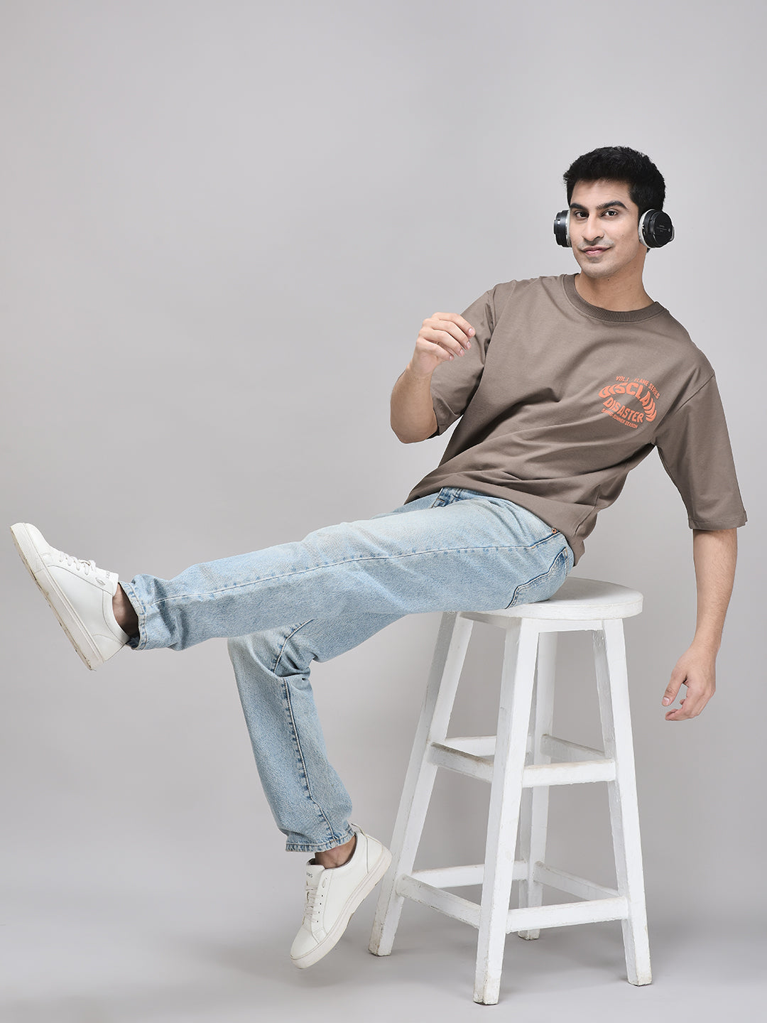 Claystone brown oversized t-shirt styled with light denims – seated casual pose