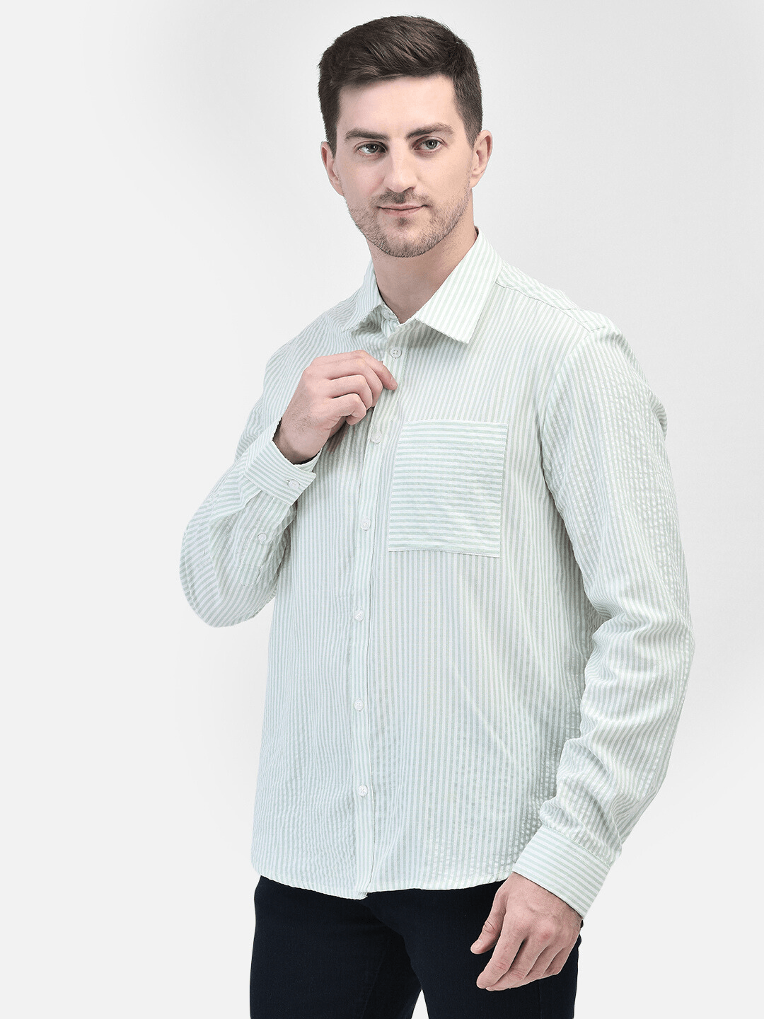 Man slightly adjusting collar – green striped cotton shirt front view