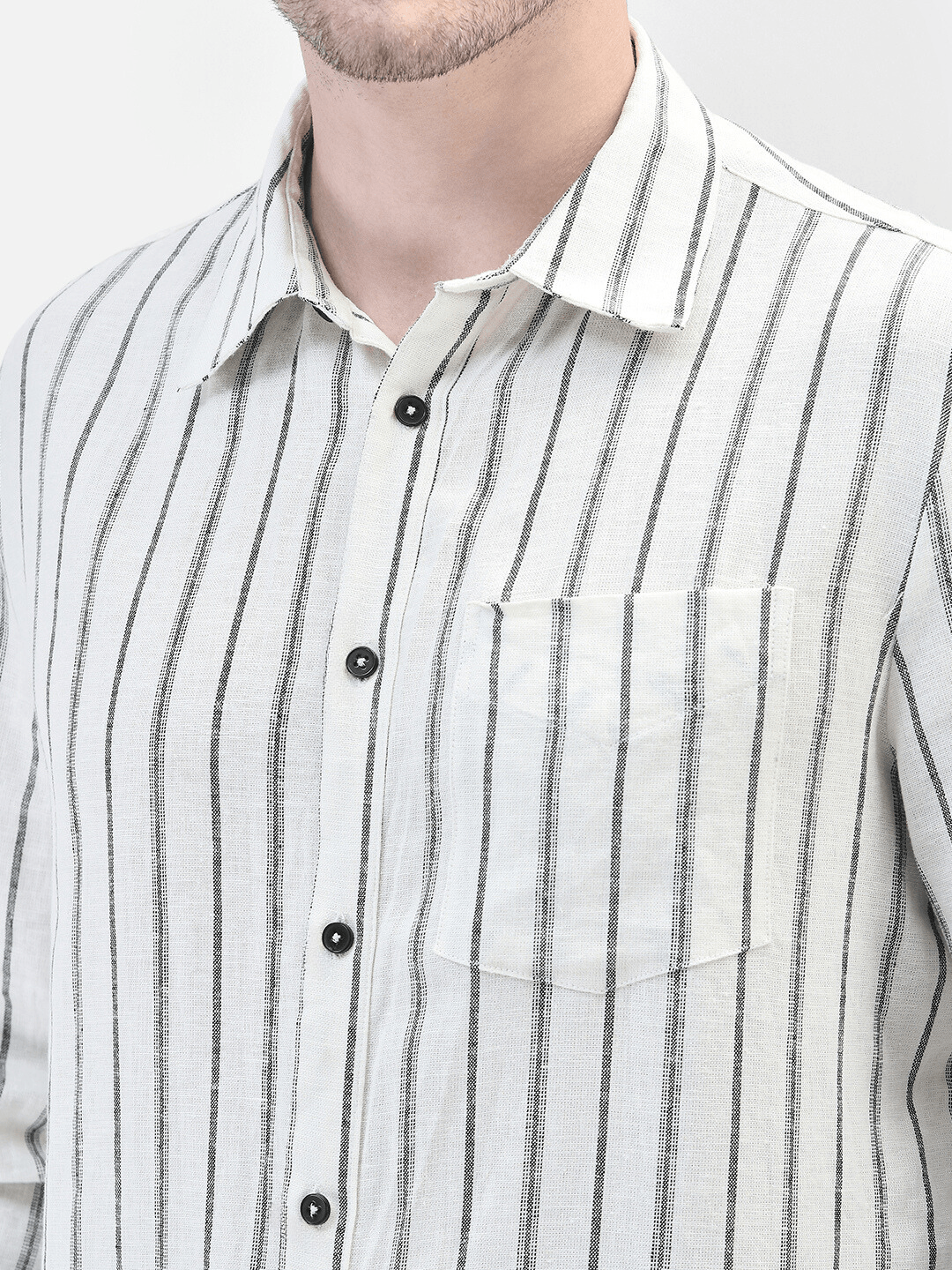 Close-up of vertical black stripes, buttons, and linen texture on off-white fabric