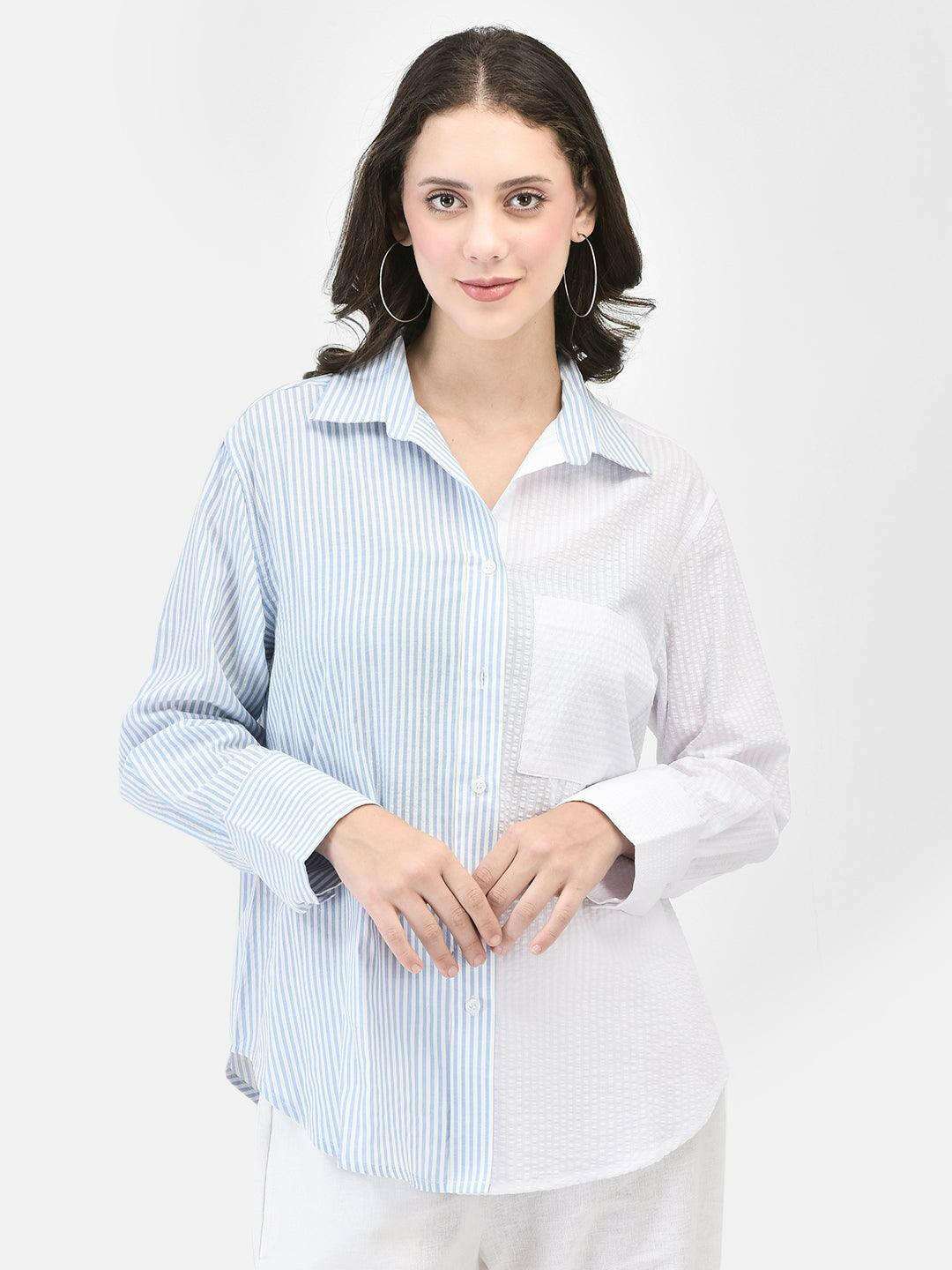 Front view of woman in nautical blue striped shirt – hands clasped at waist
