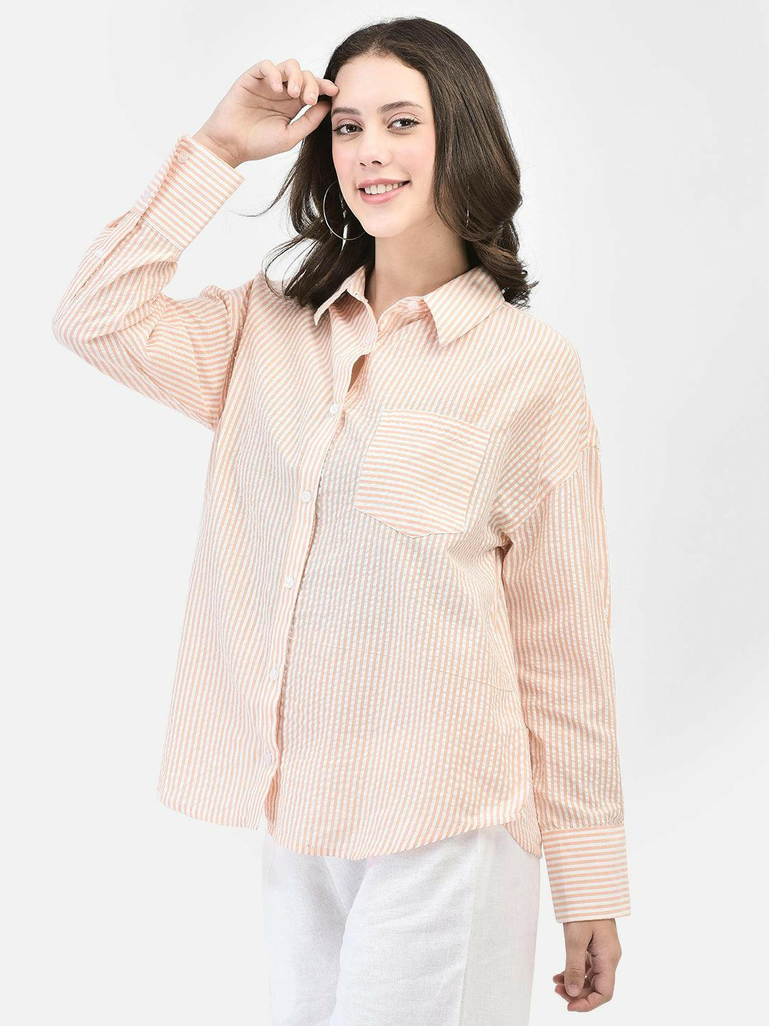 Woman posing with hand in hair – peach striped cotton shirt with oversized sleeves