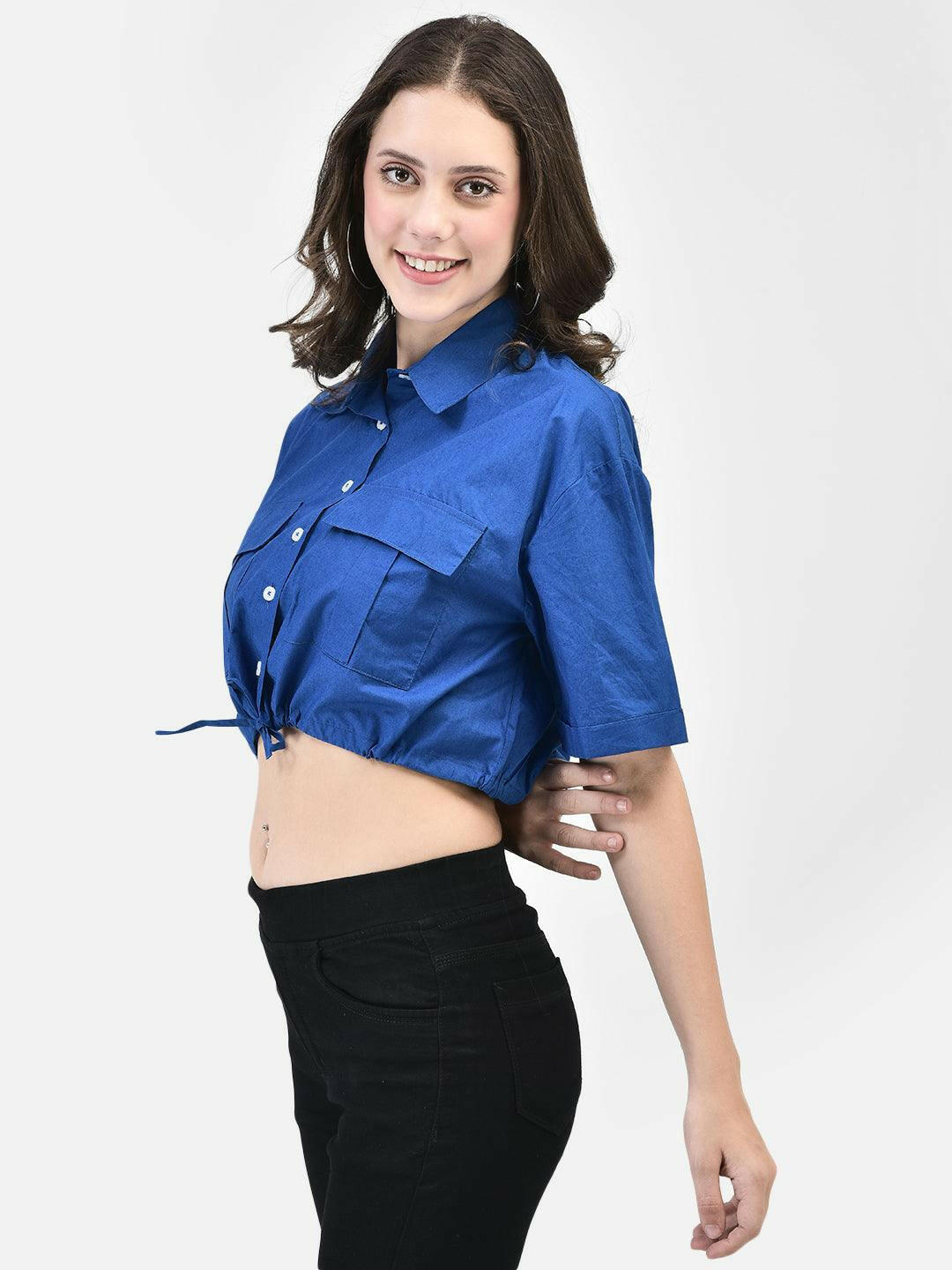 Side view of woman tying front knot of blue cropped shirt