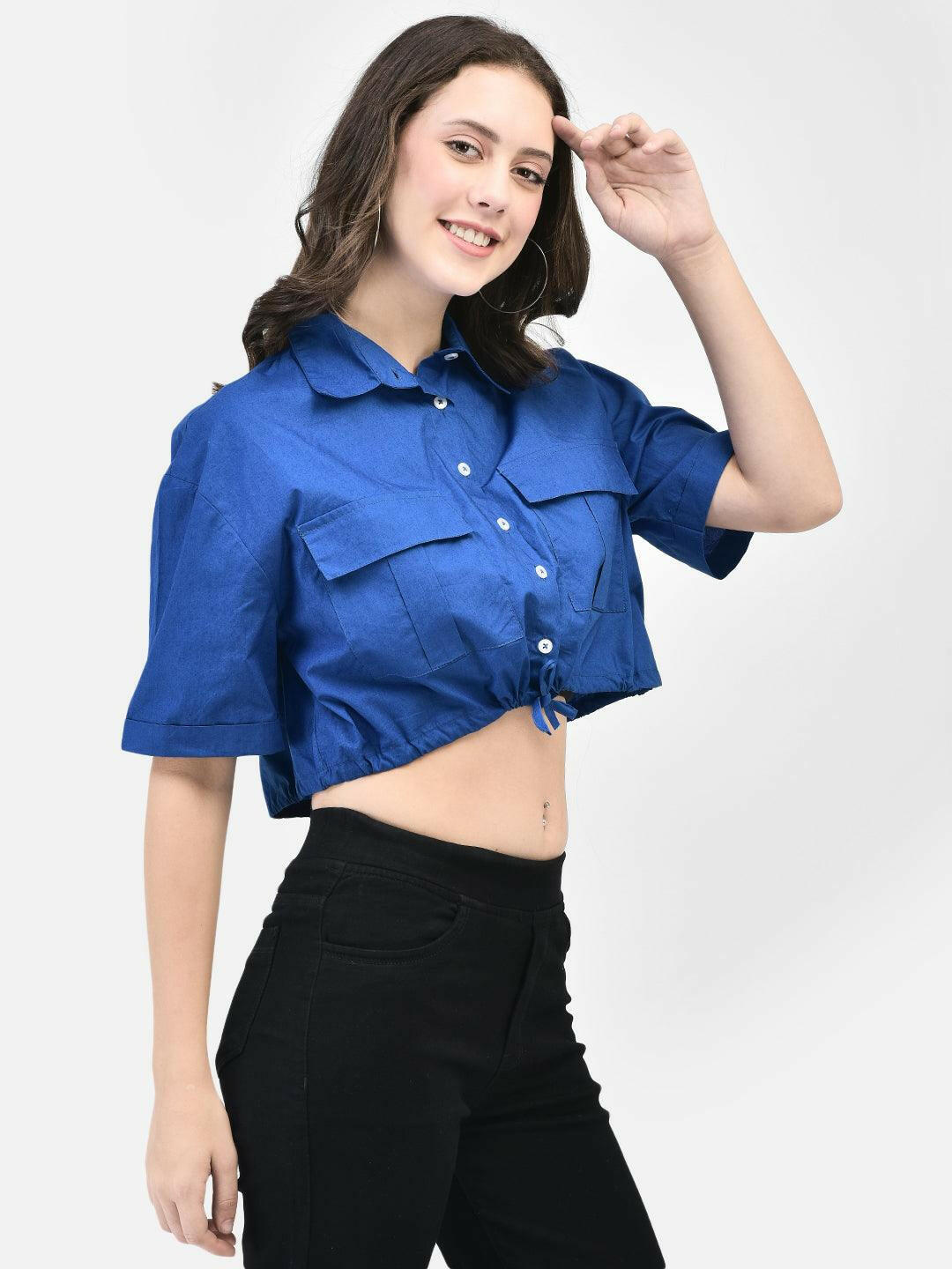 Model posing with hand in air wearing cobalt blue crop shirt