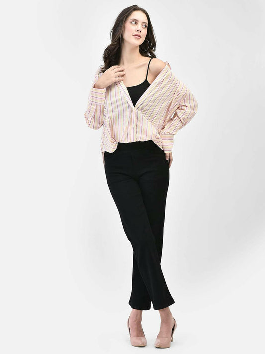 A female model wearing a pink and blue striped seersucker shirt with long sleeves and dropped shoulders, paired with black pants.