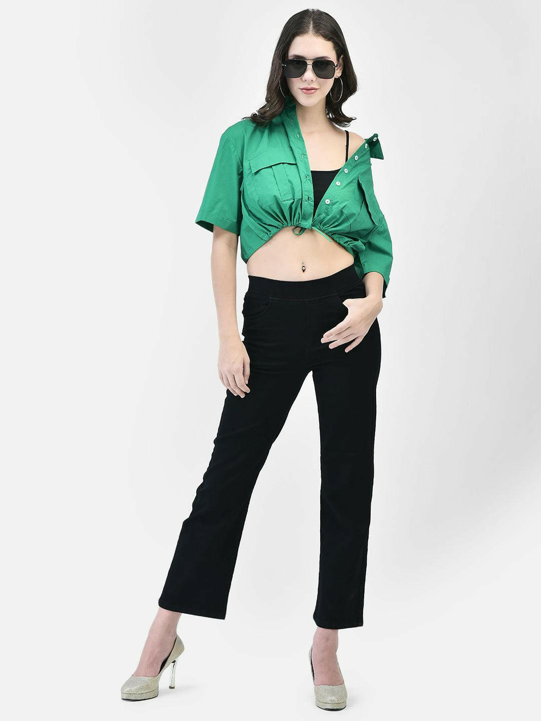 Woman wearing green cropped cotton shirt with tie-front, styled with black pants and heels – front pose.