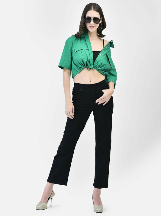 Woman wearing green cropped cotton shirt with tie-front, styled with black pants and heels – front pose.