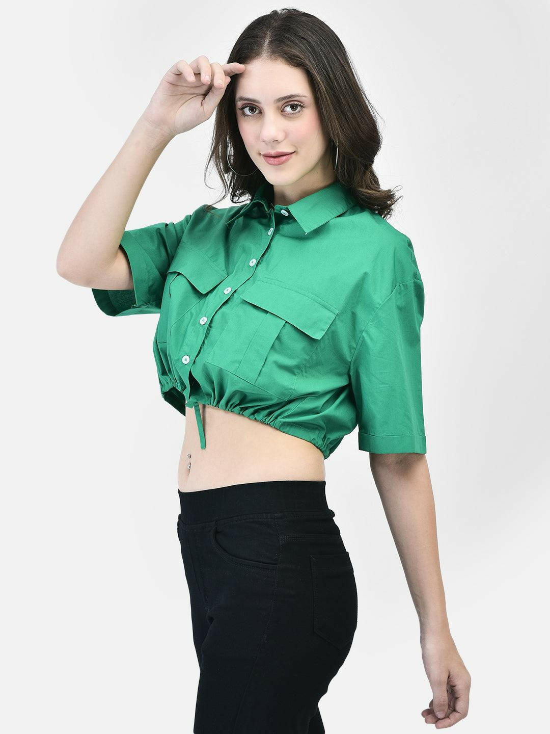 Side view of woman wearing green cotton cropped shirt showing tie-front detail and relaxed sleeve.