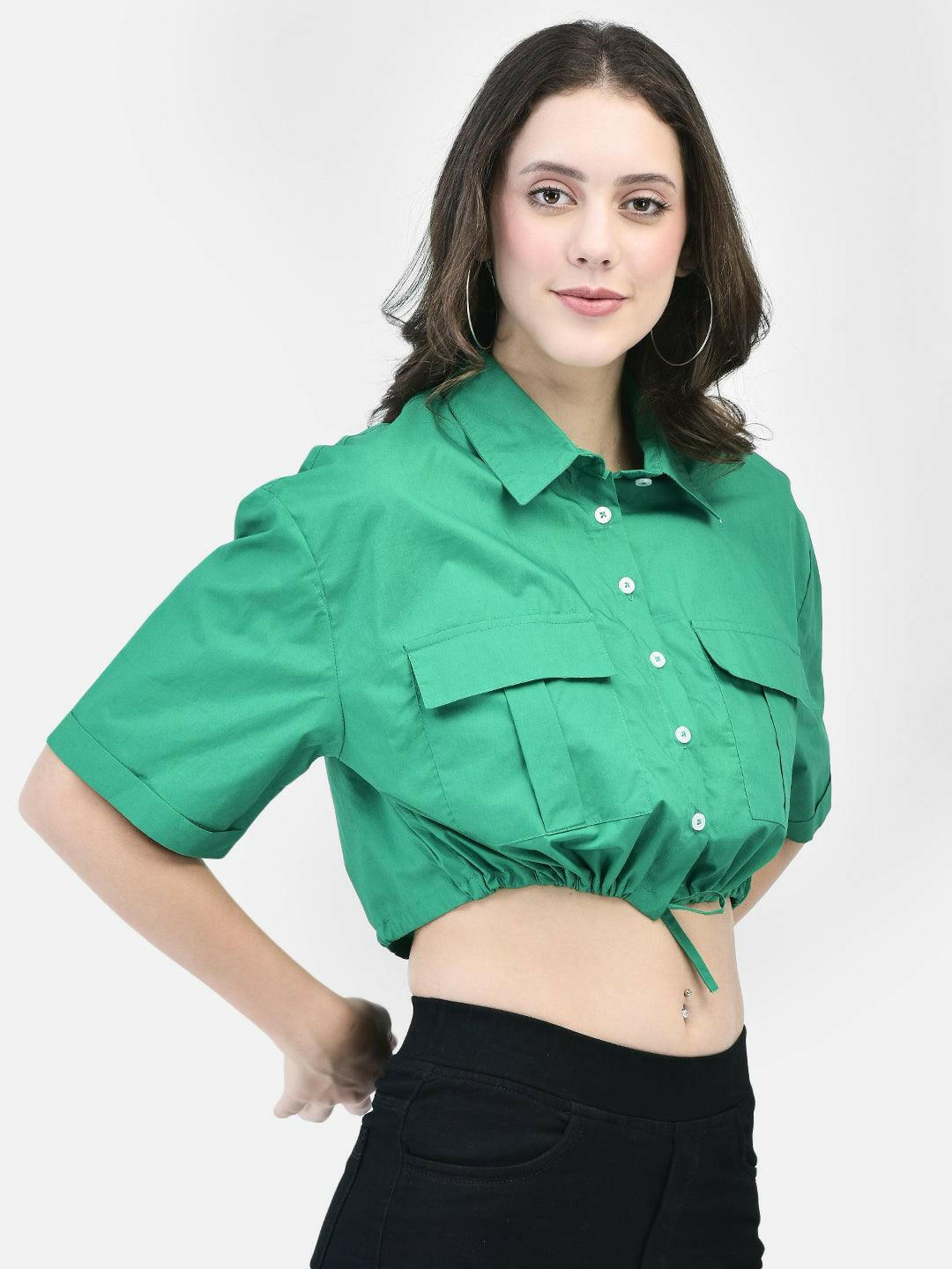 Model showcasing green summer shirt for women – casual pose with black trousers.