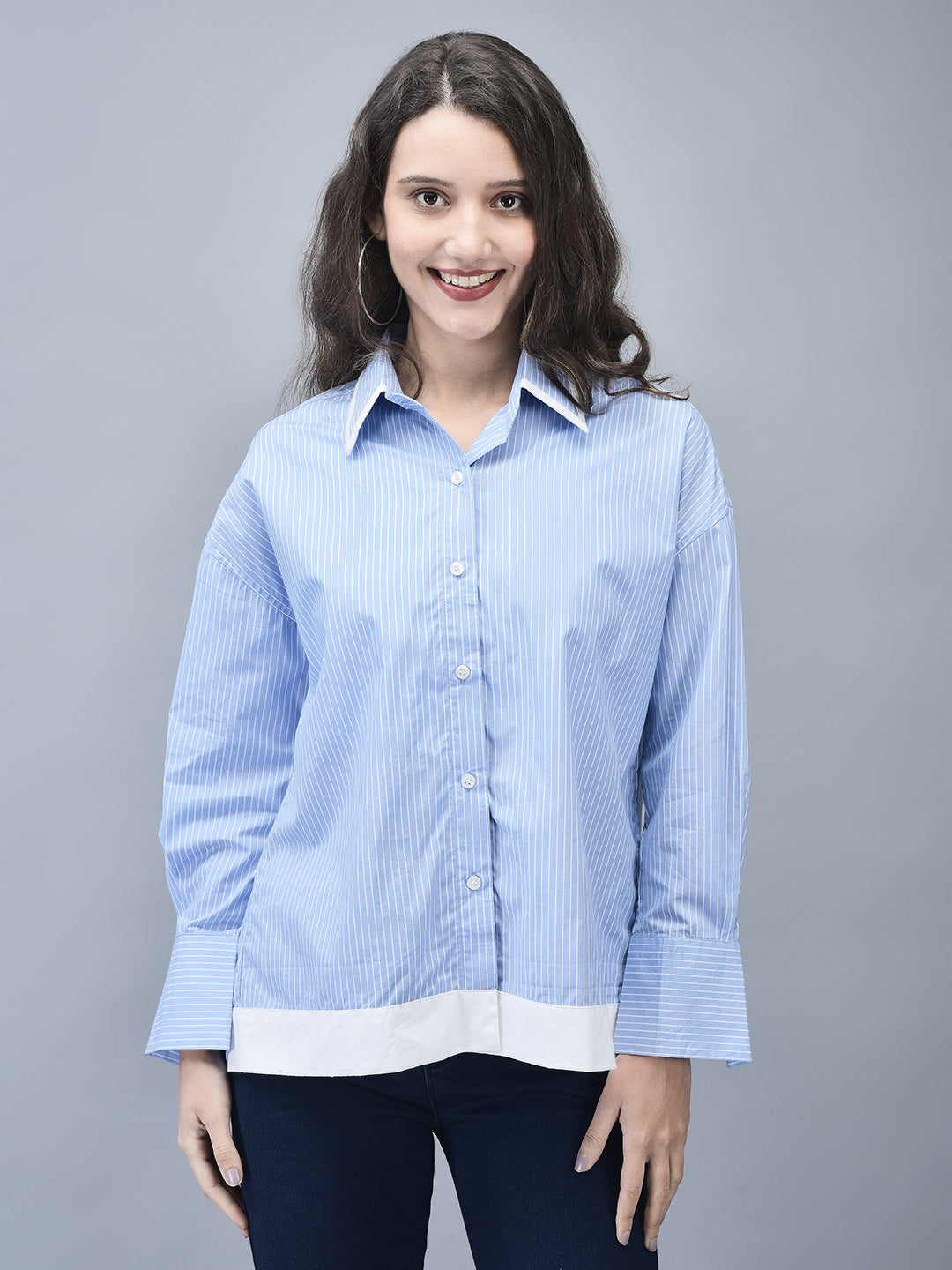 Smiling model in relaxed blue pinstripe shirt, standing straight