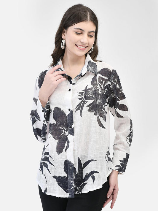 A woman wearing a black and white floral shirt with long sleeves and an oversized fit.