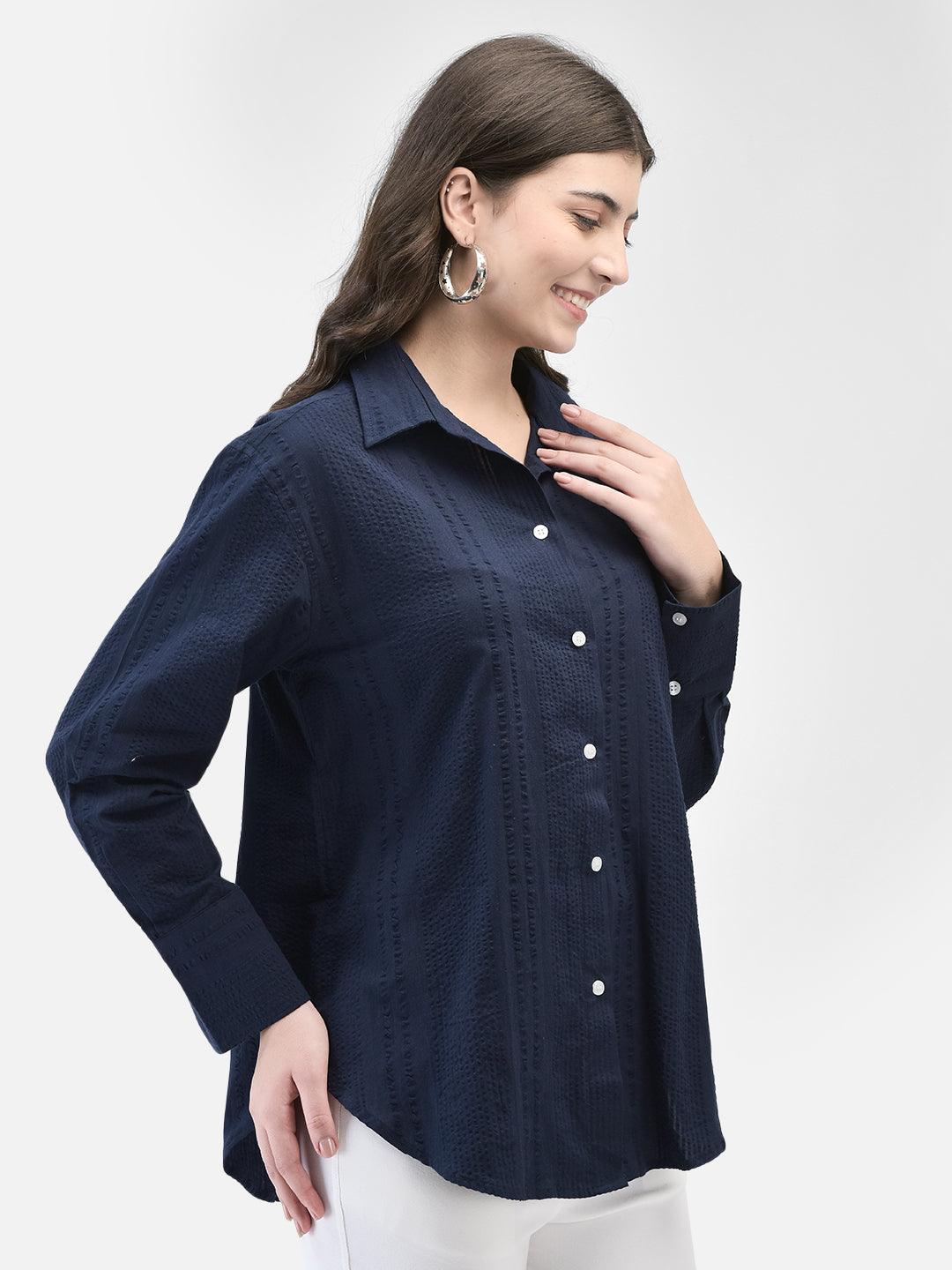 Model posing in blue cotton seersucker shirt with hand on collar, casual expression