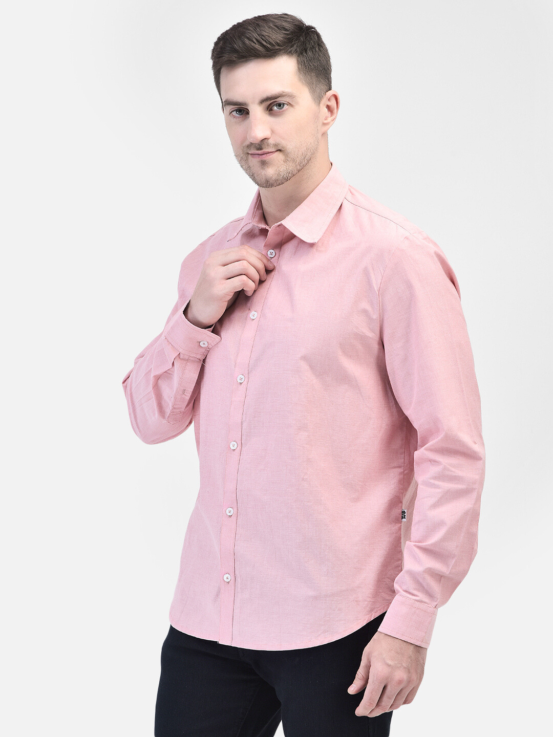 Man adjusting collar of lightweight pink chambray shirt – semi-casual styling.