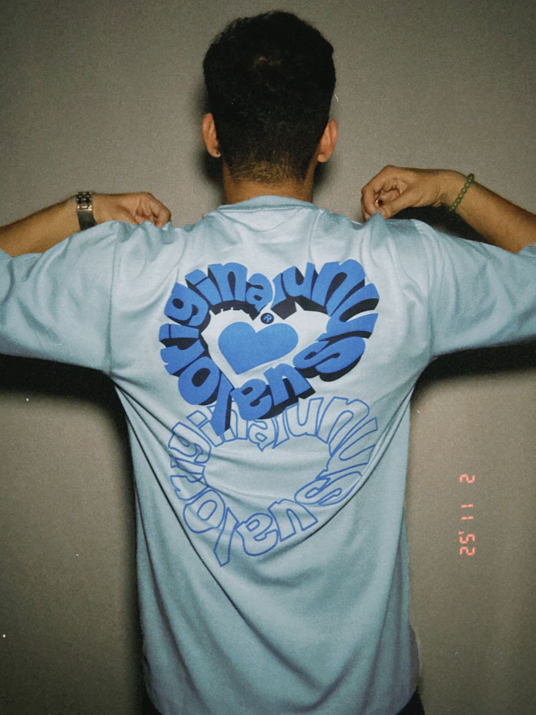 Person wearing a light blue t-shirt with a blue design on the back.