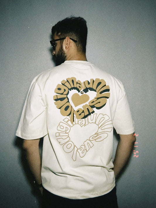 A person wearing a beige oversized t-shirt with a heart and text design on the back.
