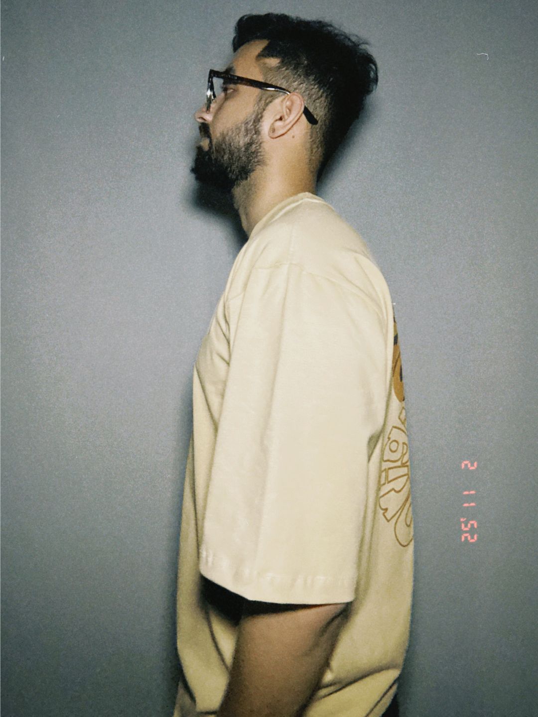 Person wearing a beige shirt against a plain background