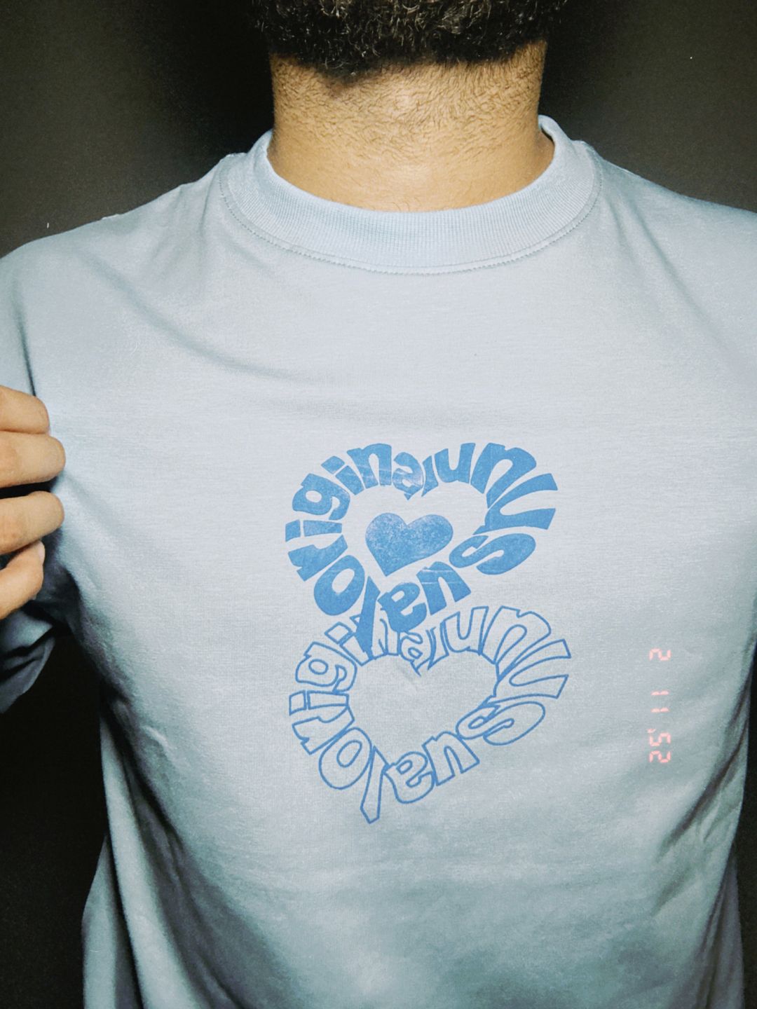Person wearing a light blue t-shirt with a graphic design.