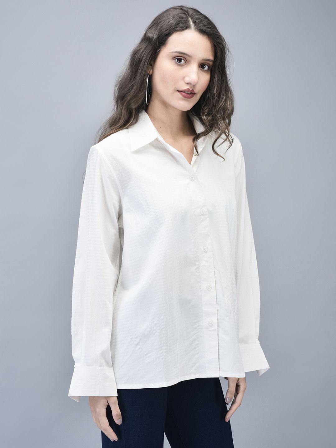 Side view of the model in longline textured white shirt and navy pants.