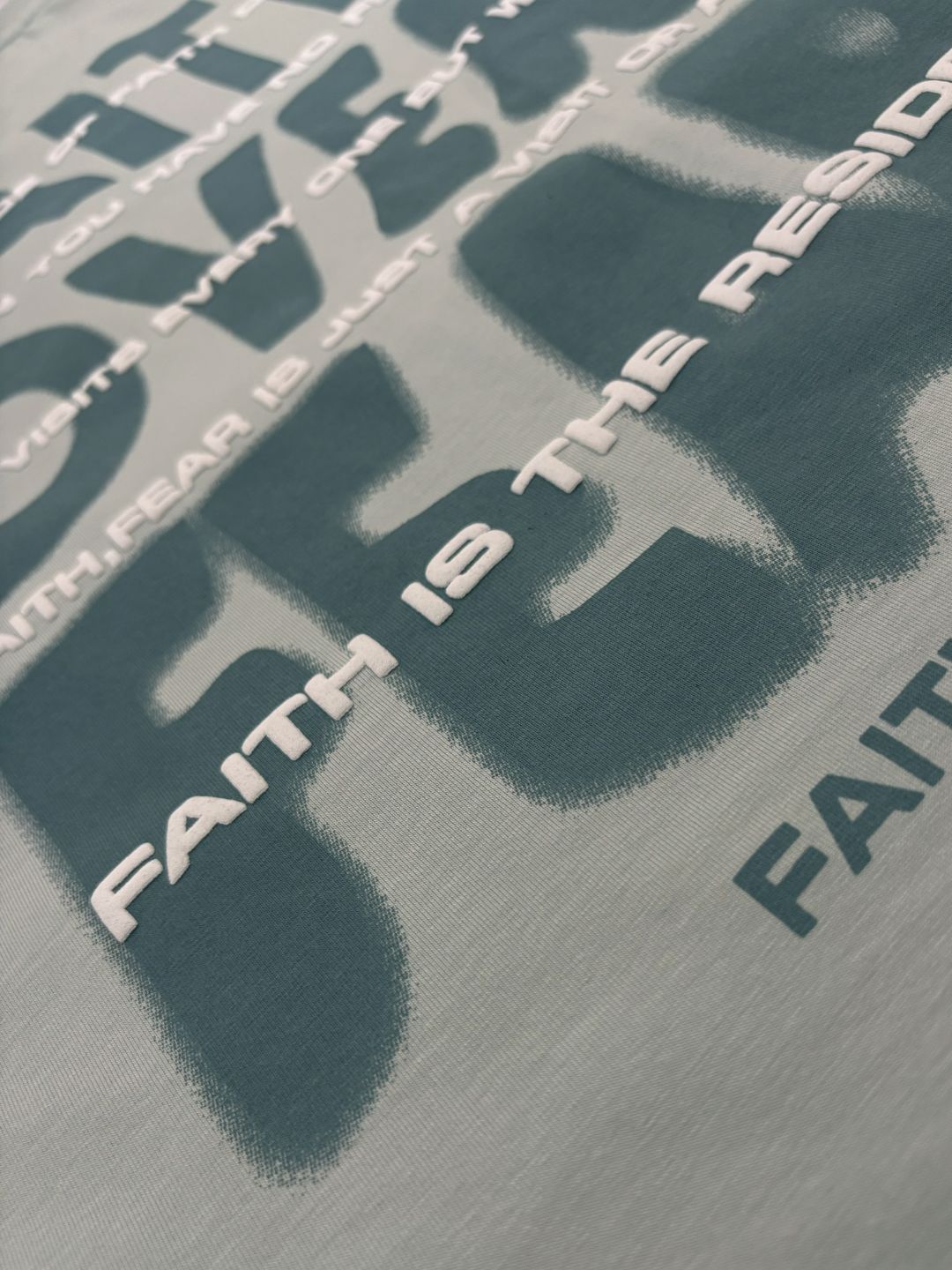 Close-up of 'Faith is the Resi' text on a textured surface.