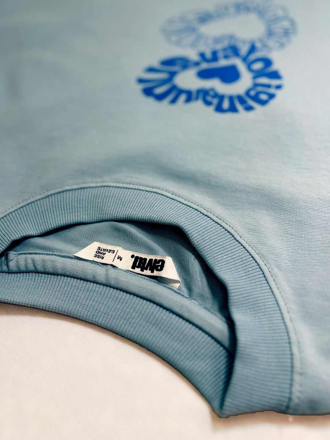 Light blue sweatshirt with a logo and brand label.