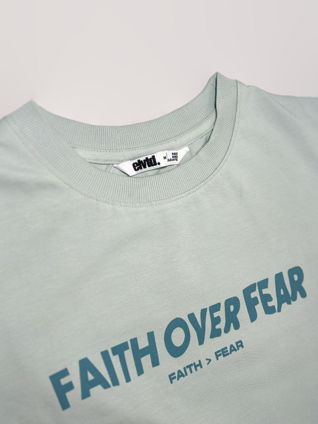 Light gray t-shirt with 'Faith Over Fear' text on a plain background.