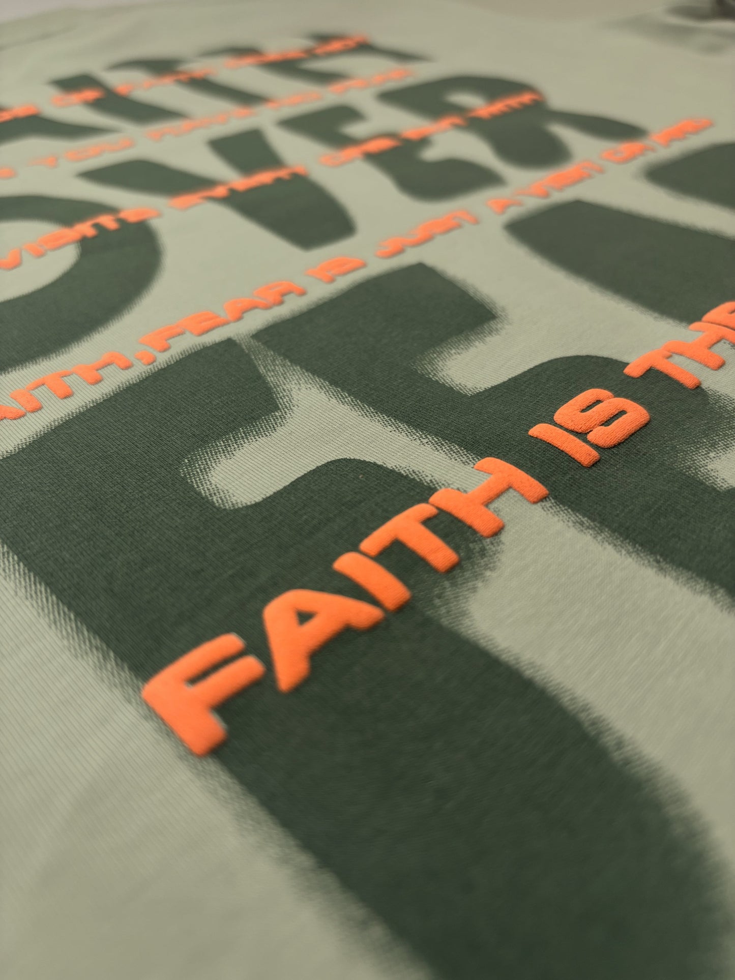 Close-up of 'FAITH IS THE OIL' text on a green background