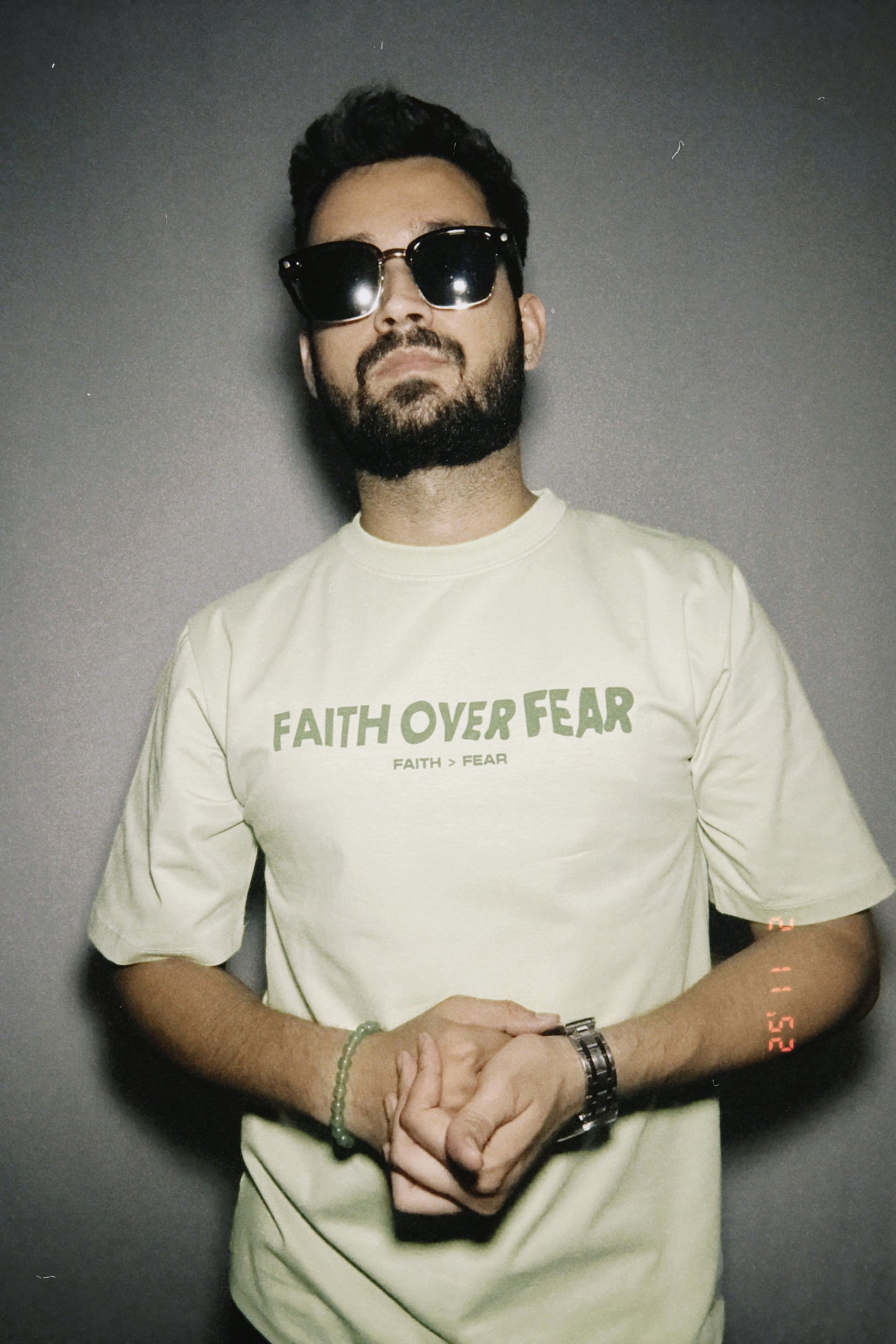 Person wearing a t-shirt with 'Faith Over Fear' text, standing against a plain background.